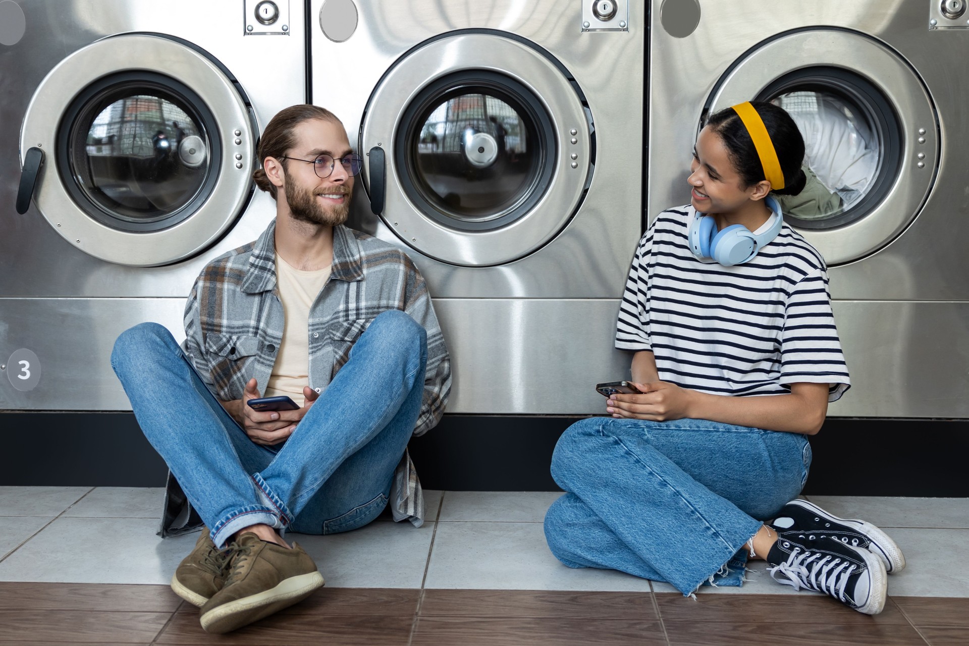 Man and woman waiting together in laundromat, communicating while washing their clothes