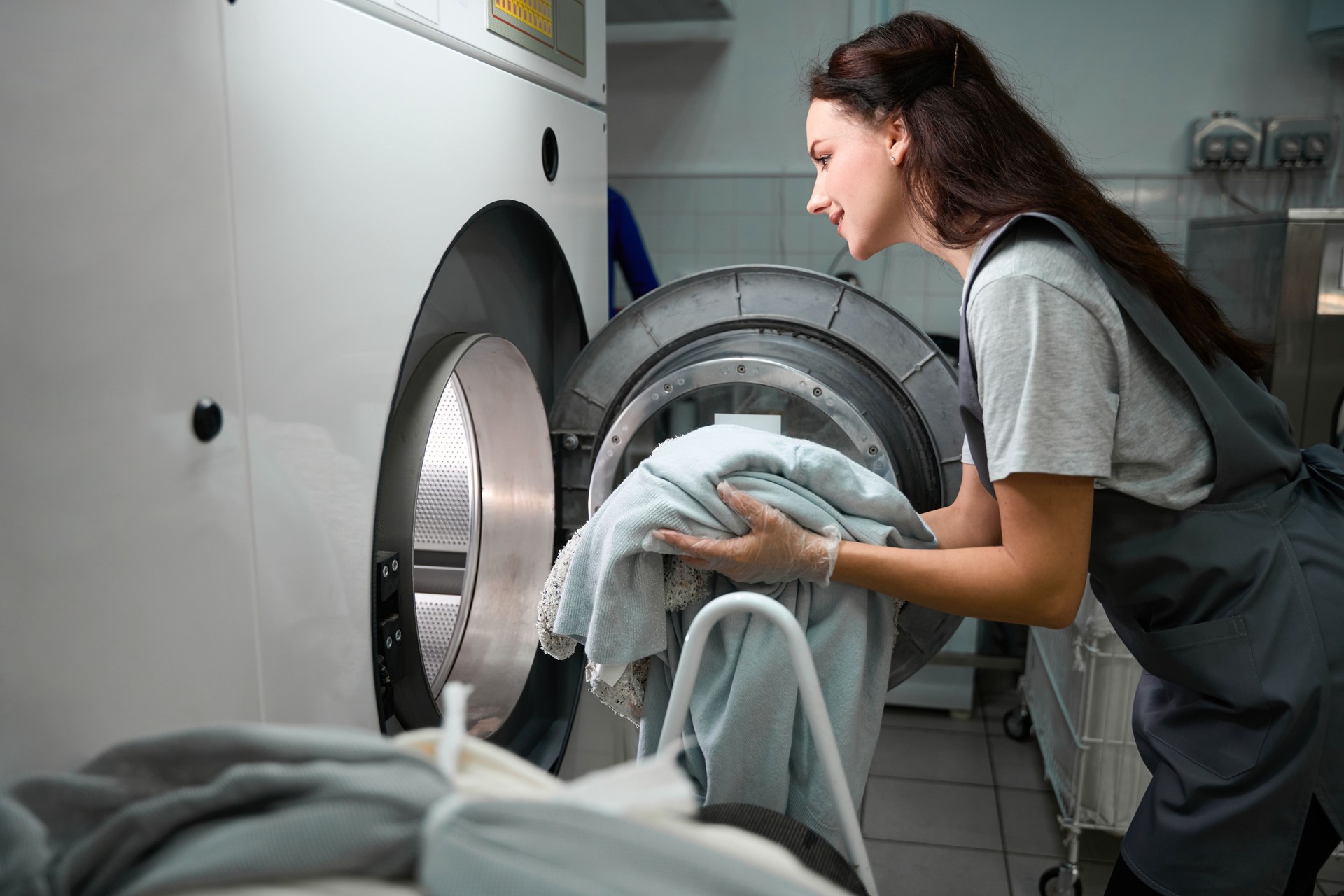 Dry cleaner worker loading drum-machine with sorted clothes