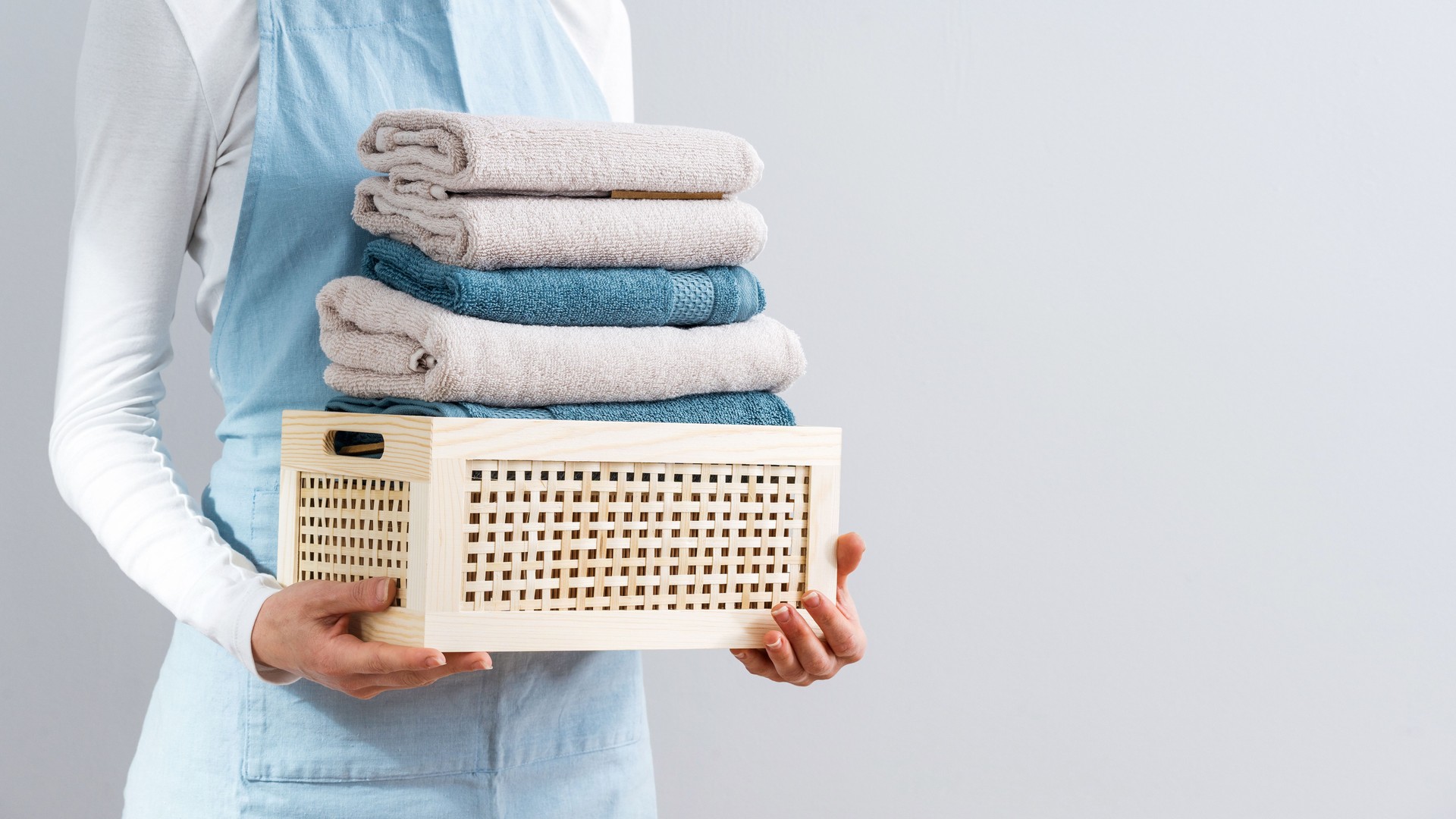 Woman in apron holding storage box with fresh towels