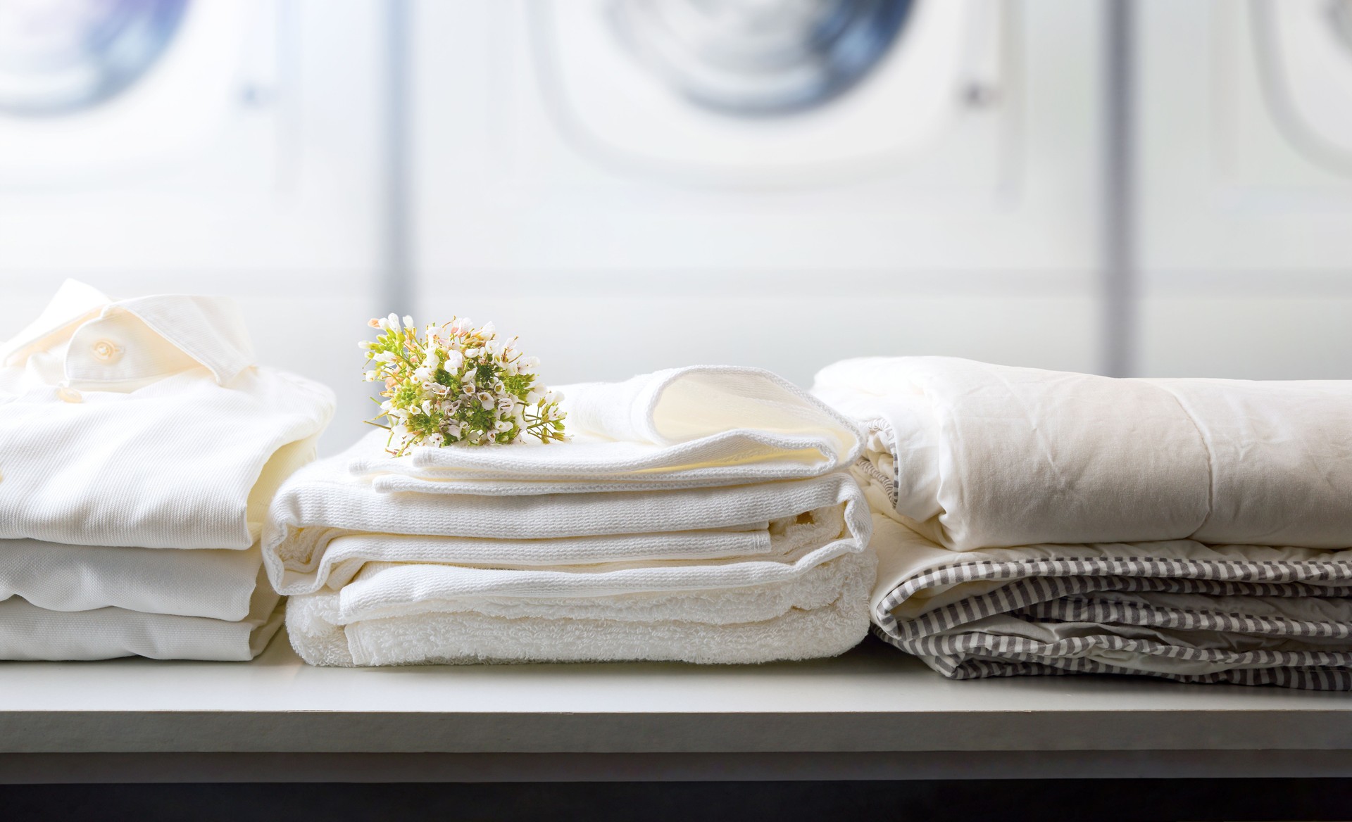 Self-service laundry with textiles on bench and washing machines background
